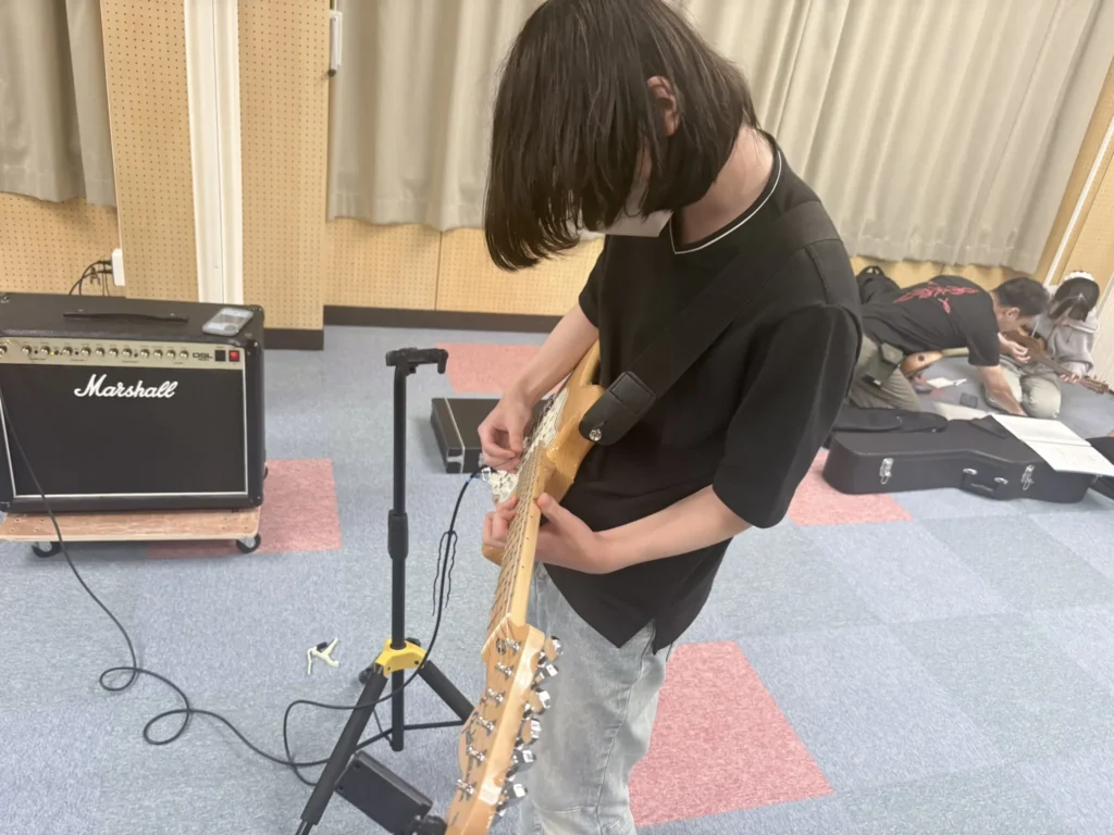 ほっこりダベリバの「音楽ひろば」で、エレキギターを弾く参加者